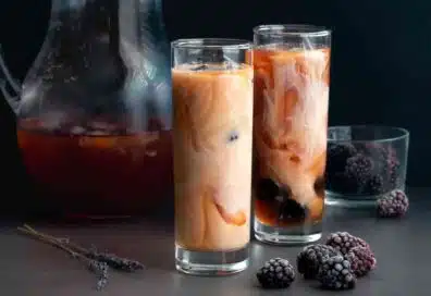 Two glasses of iced tea latte with creamer and blackberries