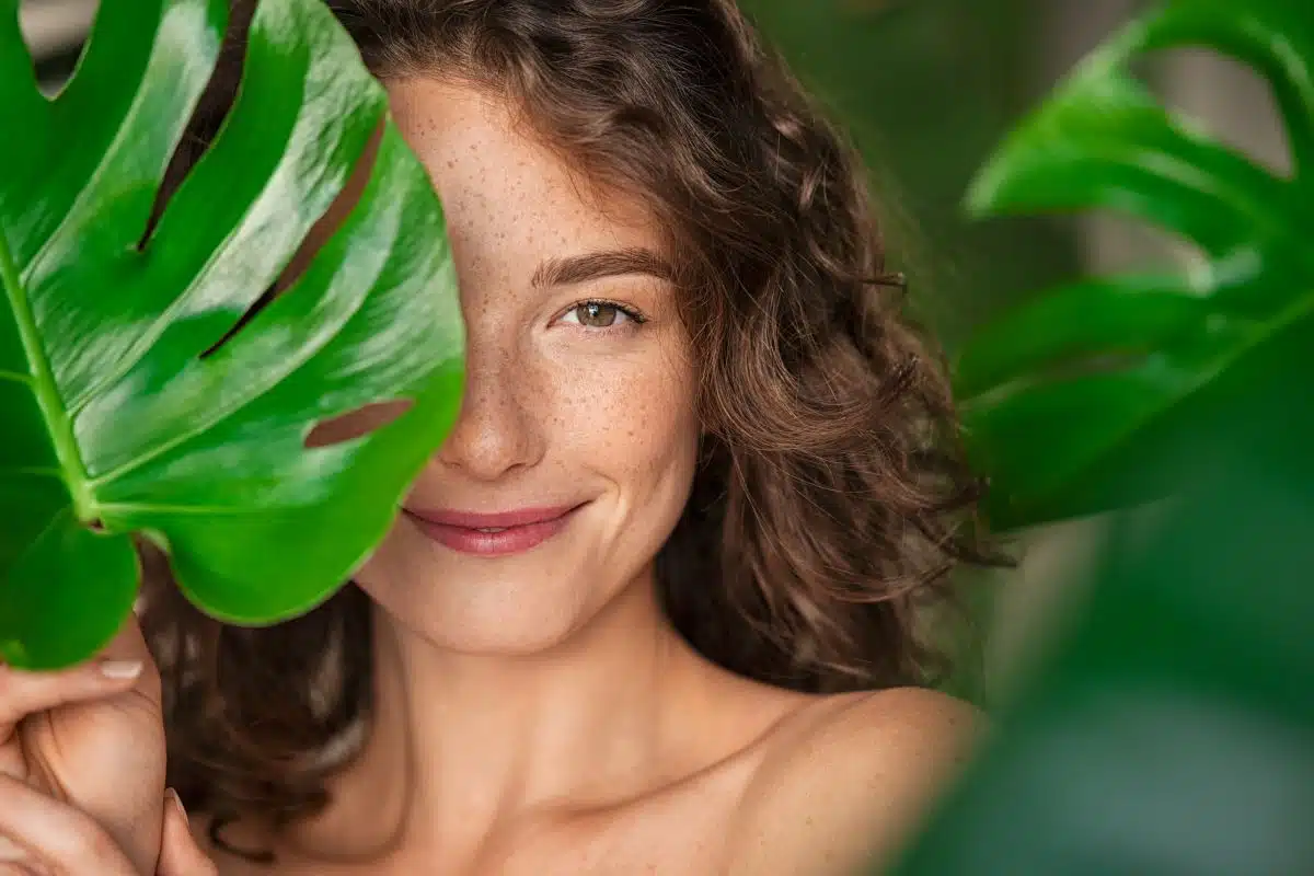 Happy woman whose face is half covered by a leaf