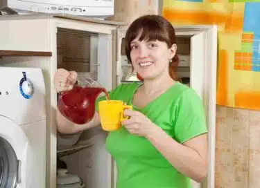 Woman pouring tea from a pitcher in the refrigerator