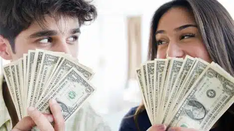 Man and woman holding up a fan of $1 bills