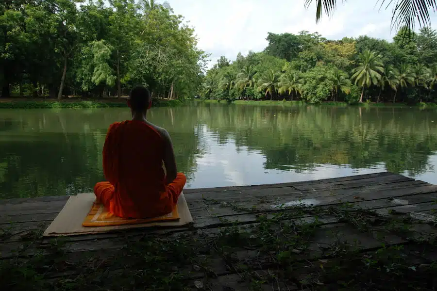 monk sitting on river bank in meditative state