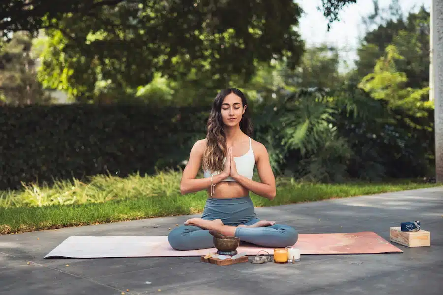woman meditating on yoga mat in park
